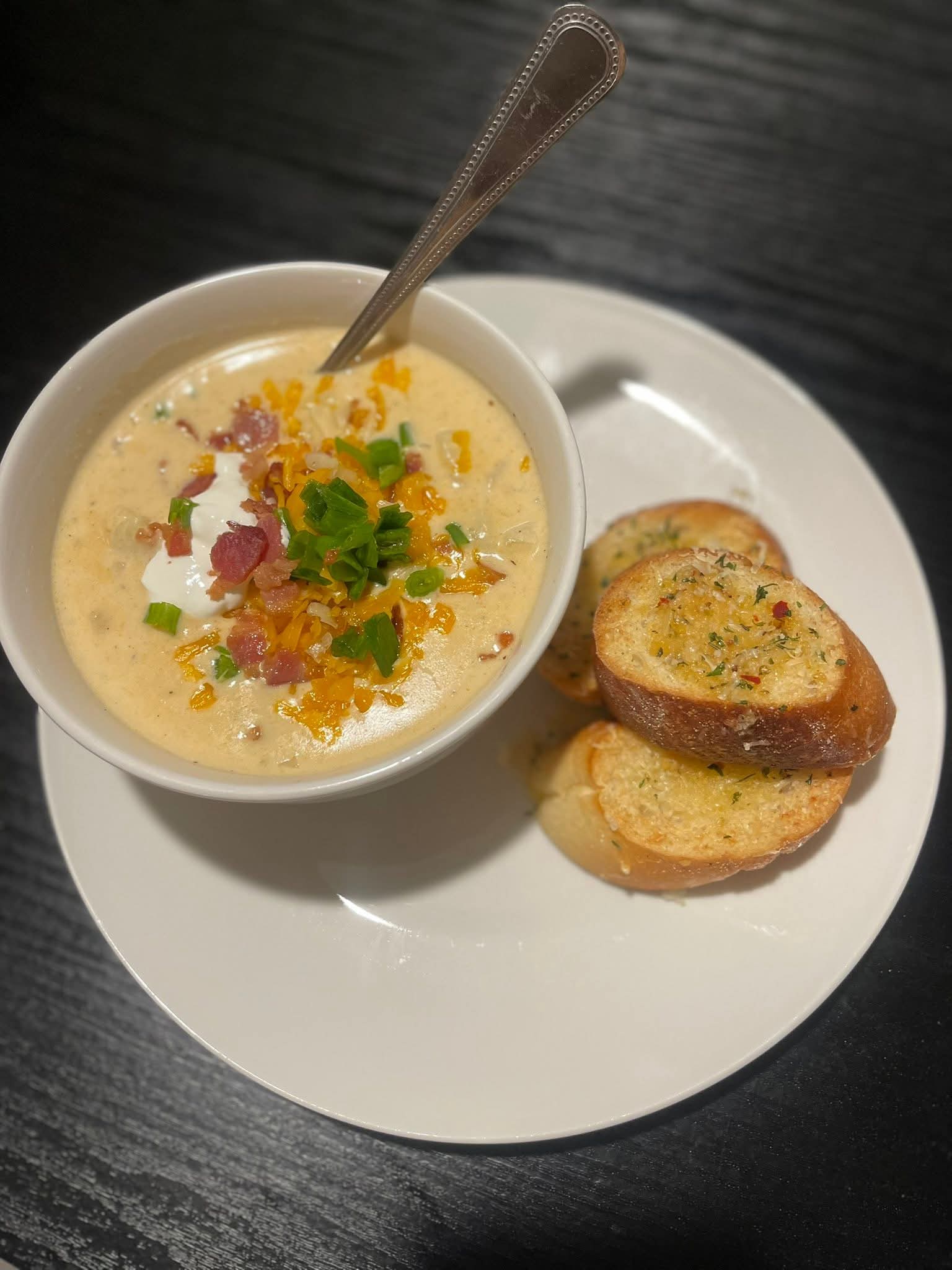 Loaded potato soup served in a white bowl with toast